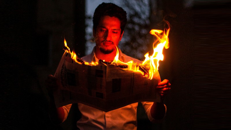 Mann mit brennender Zeitung, Foto: Baran Lotfollahi auf unsplash