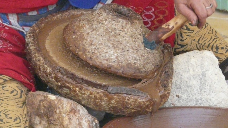 Eine Frau beim Mahlen mit der Arganöl-Mühle